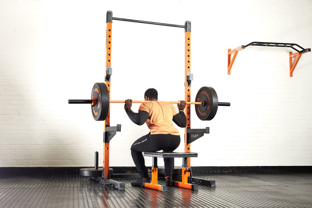 Man doing a box squat on a Mirafit Squat Box with an Olympic barbell and bumper plates