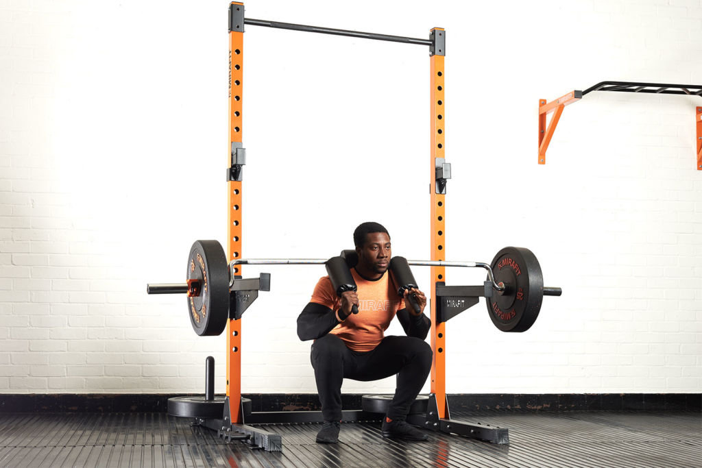Man doing pause squats with a Mirafit 7ft Olympic Safety Squat Bar
