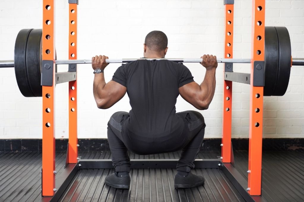 Man squatting in the Mirafit M200 Power Rack