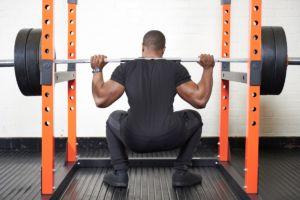 Man squatting in a Mirafit M200 Power Rack