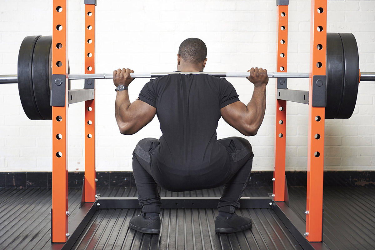Man squatting in a Mirafit M200 Power Rack