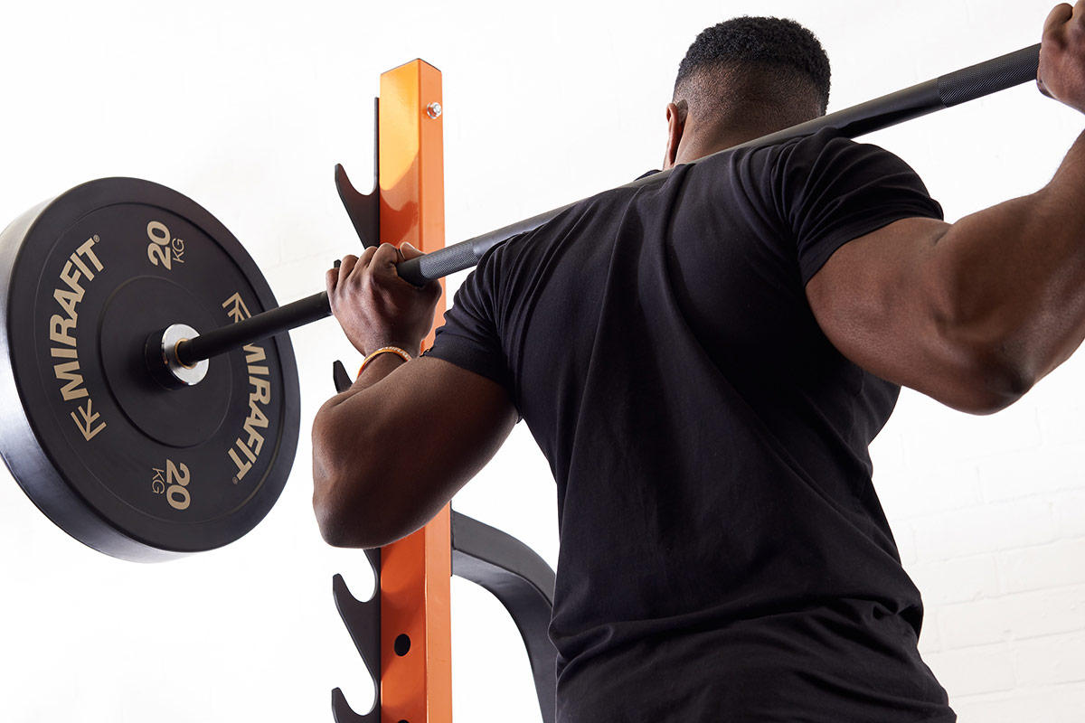 Man squatting using Mirafit Black Olympic Rubber Bumper Plates