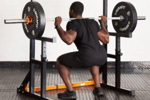 Man squatting in a Mirafit M130 Adjustable Squat and Bench Press Rack with 20kg weight plates