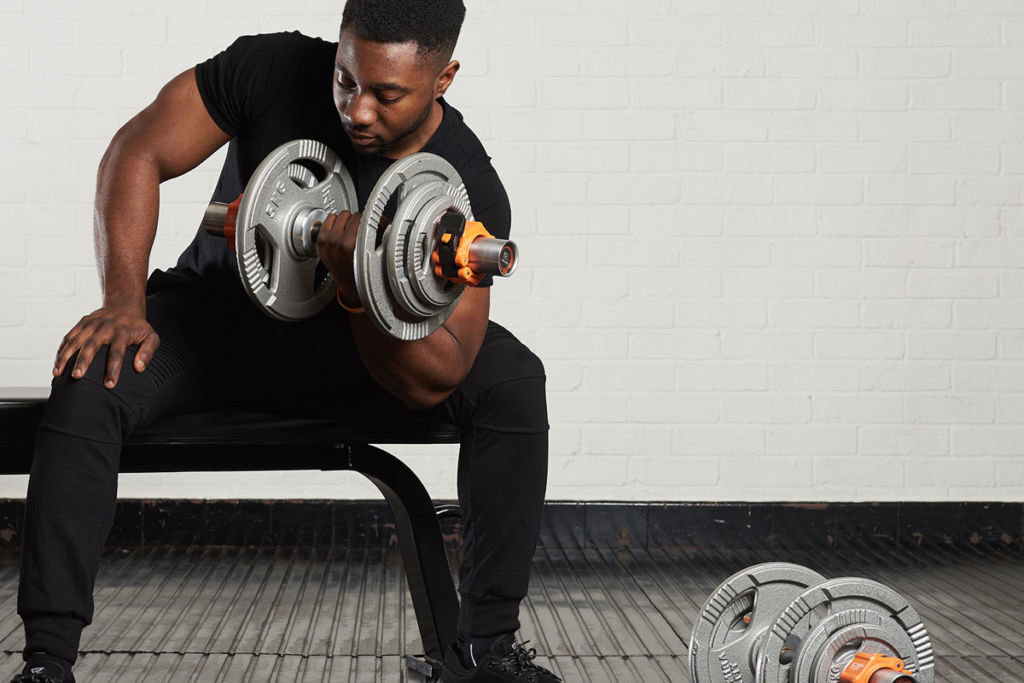 Mirafit Thick Grip Olympic Dumbbell Bars Man doing concentration curls with Mirafit Thick Grip Olympic Dumbbell Bars