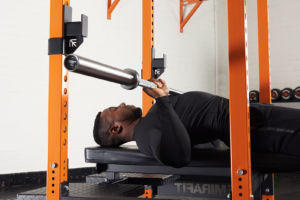 Man bench pressing with a Mirafit Olympic Barbell