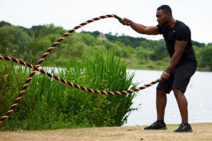 Man doing alternating waves with a Mirafit 38mm Black & Orange Battle Rope