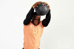 Man performing an overhead slam with a Mirafit tyre tread 10kg slam ball