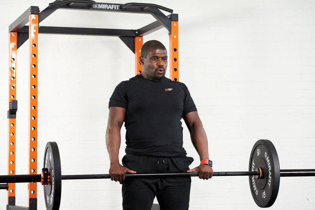 Mirafit Black Olympic Rubber Bumper Plates - 10kg plates Man deadlifting 10kg weight plates in front of a Mirafit Power Rack