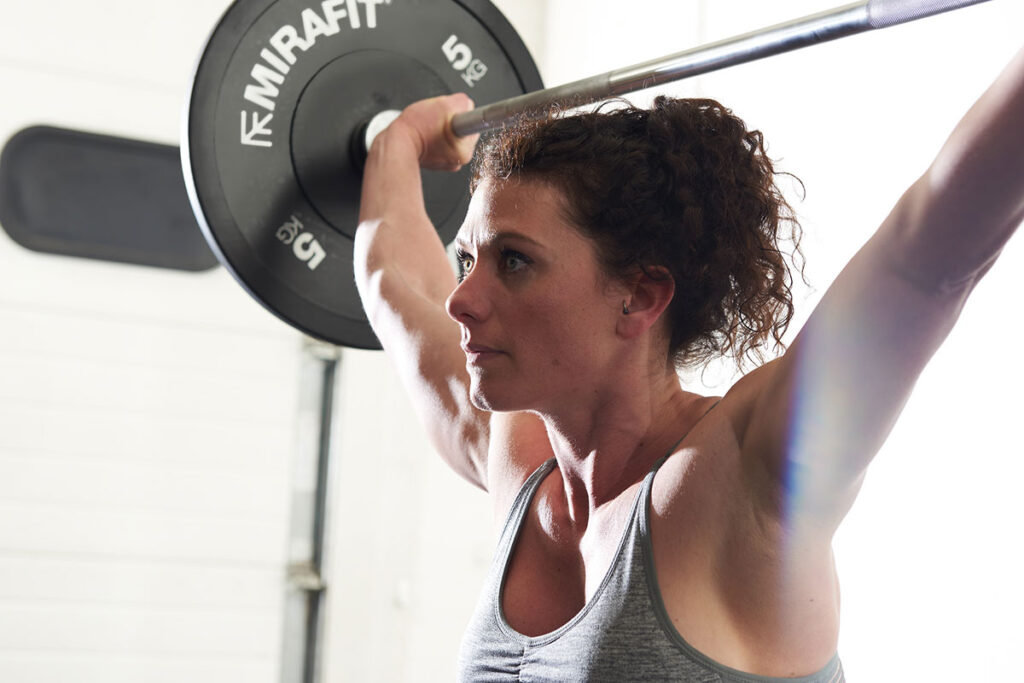 Mirafit Black Olympic Rubber Bumper Plates - 5kg weight plates Woman squatting with a 5kg weight plate