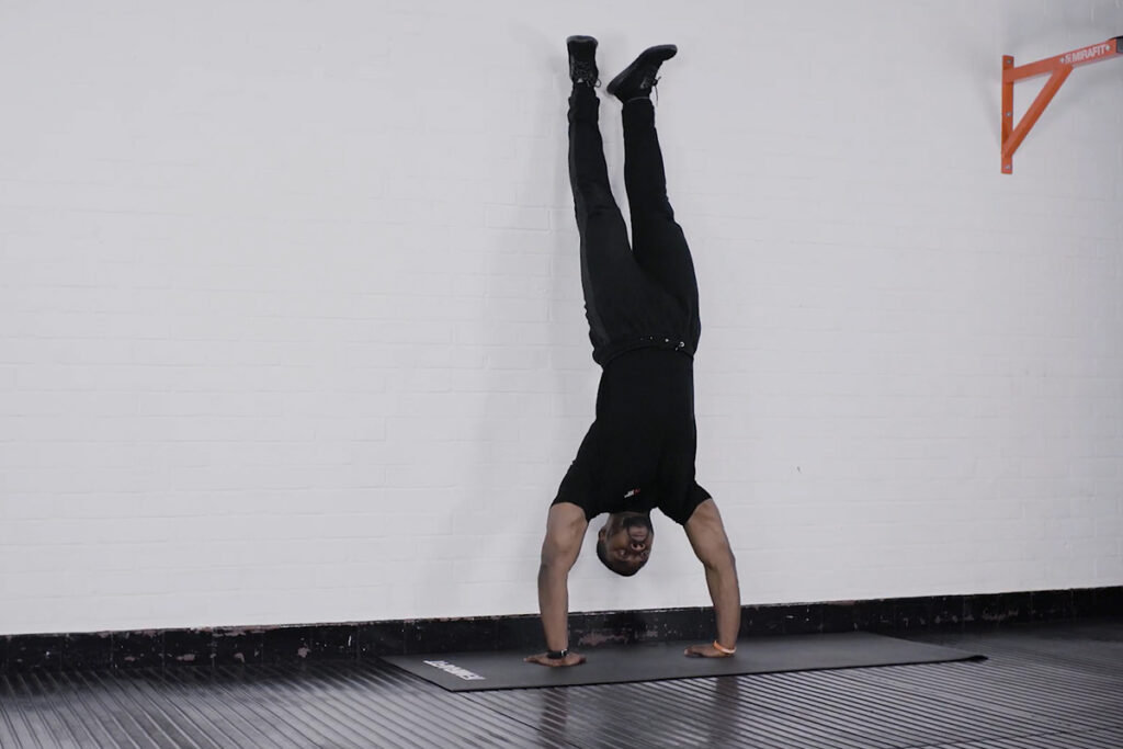 Handstand Push Up Man performing handstand push up against a white wall on a Mirafit Exericse mat