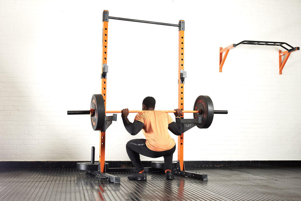 Mirafit Squat Rack Man showing a pause squat with a Mirafit barbell, Mirafit 25kg weight plates and a Mirafit squat rack