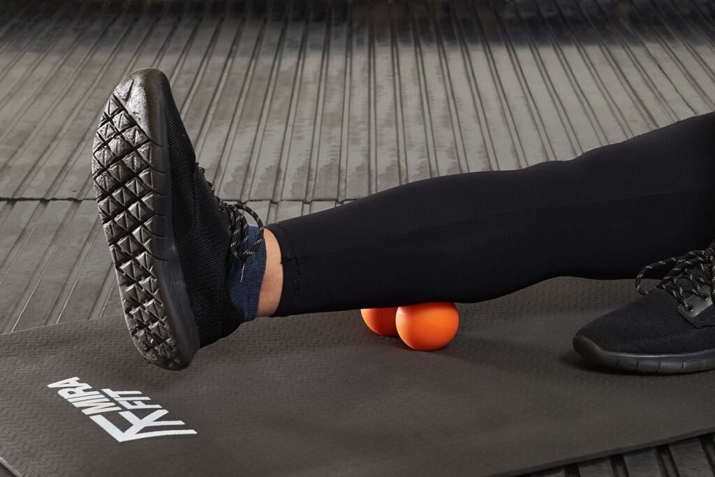 Woman massaging her calf using Mirafit Lacrosse Massage Balls