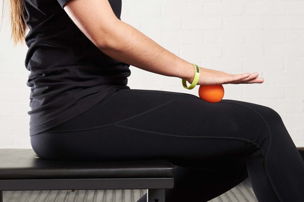 woman massaging thigh muscles using a Mirafit Lacrosse Massage Ball