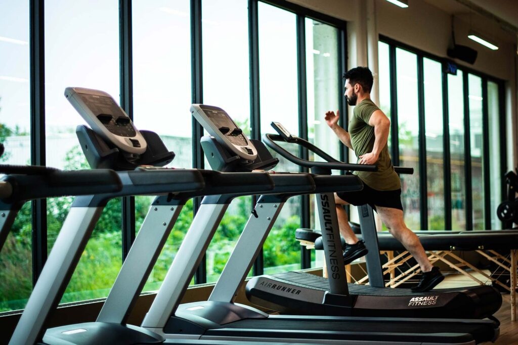 Man running on a bank of treadmills at the gym overlooking the water outside