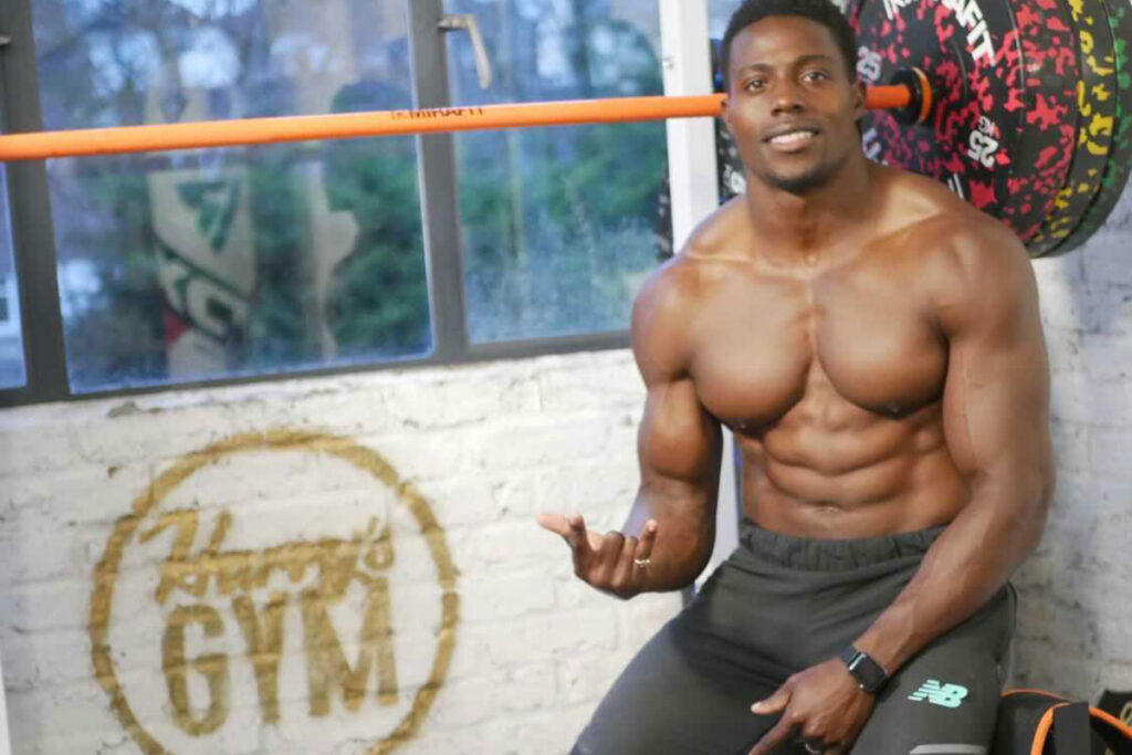 Mirafit Colour Splash Bumper Plates Olympic sprinter Harry Aikines-Aryeetey sitting in front of a Mirafit bar with weight plates.