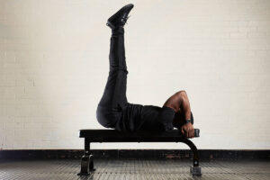 Man performing a weighted leg raise on a Mirafit M1 Flat Weight Bench