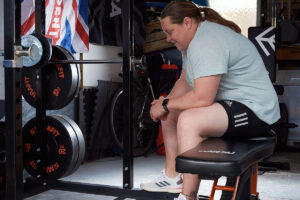 Olympic Shot Putter Sophie McKinna sitting in her Mirafit home gym
