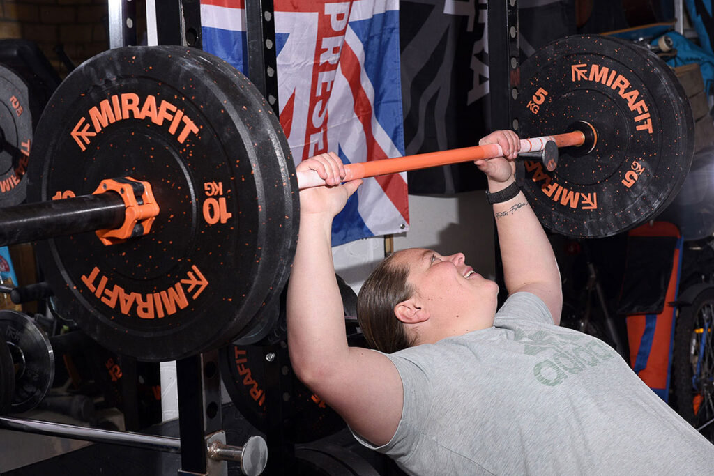 Mirafit M3 Women's 15kg Olympic Barbell Team GB Olympic Shotputter Sophie McKinna in her garage gym using a weight bench to lift 5kg weight plates and 10kg weight plates