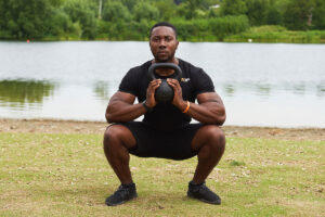 Man performing a kettlebell front squat in a bootcamp using a Mirafit Cast Iron Kettlebell