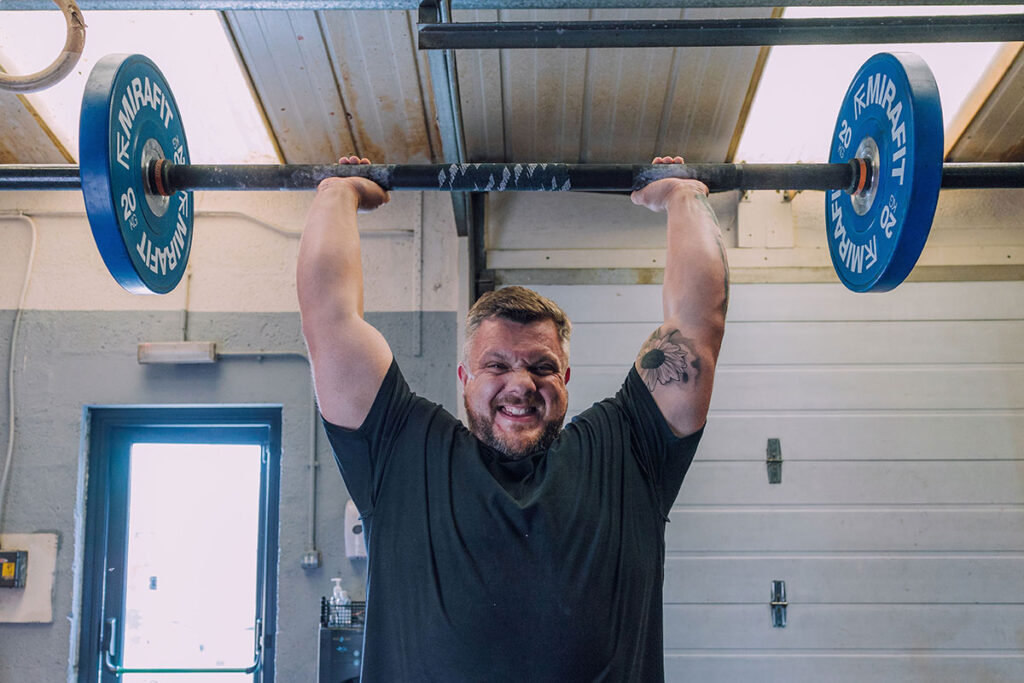 Mirafit Competition Olympic Bumper Plates Luke Stoltman performing an axle press with a Mirafit Olympic barbell and weight plates