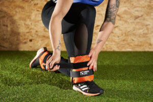 Woman at the gym strapping on Mirafit Ankle Weights