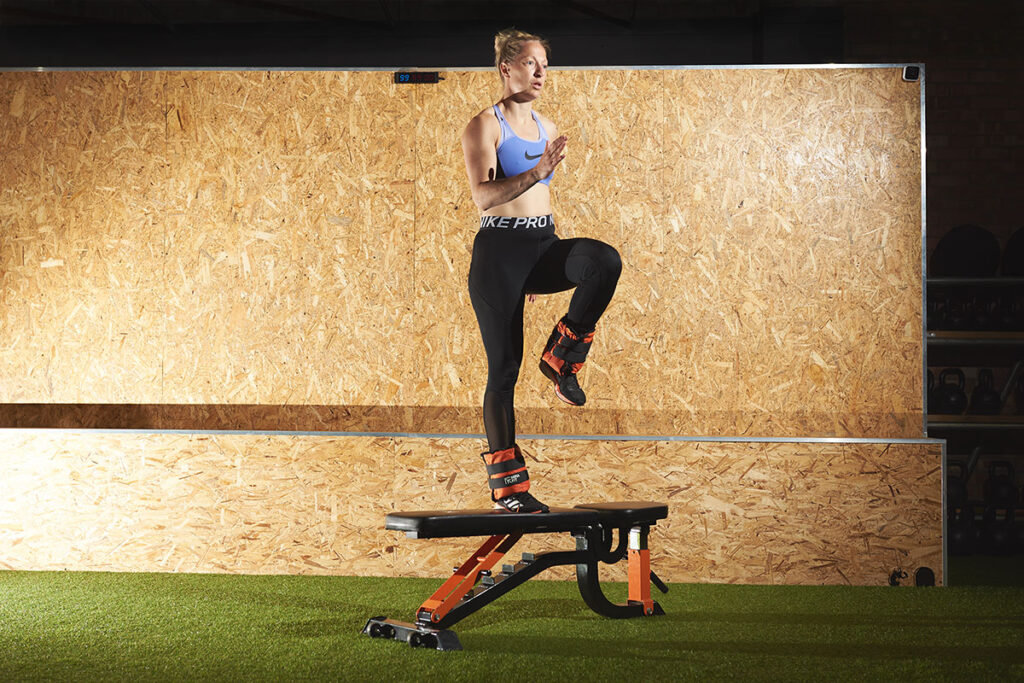 Woman performing an ankle weight step up with knee raise on a Mirafit weight bench.