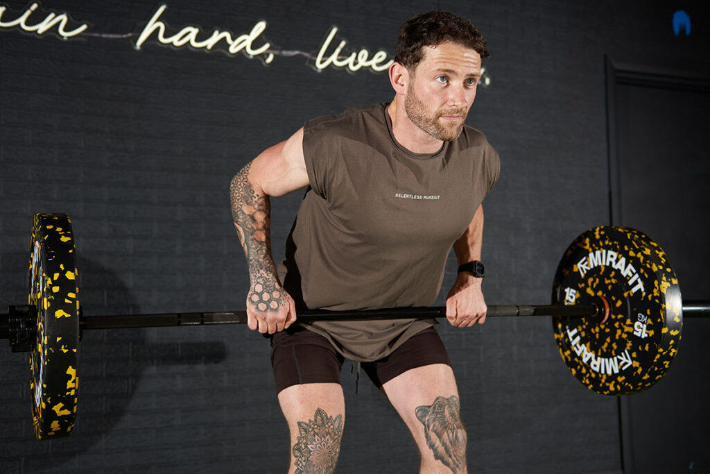 Fitness expert Jay Wall grips a Mirafit barbell while performing a Barbell Row with a Mirafit Olympic Barbell.