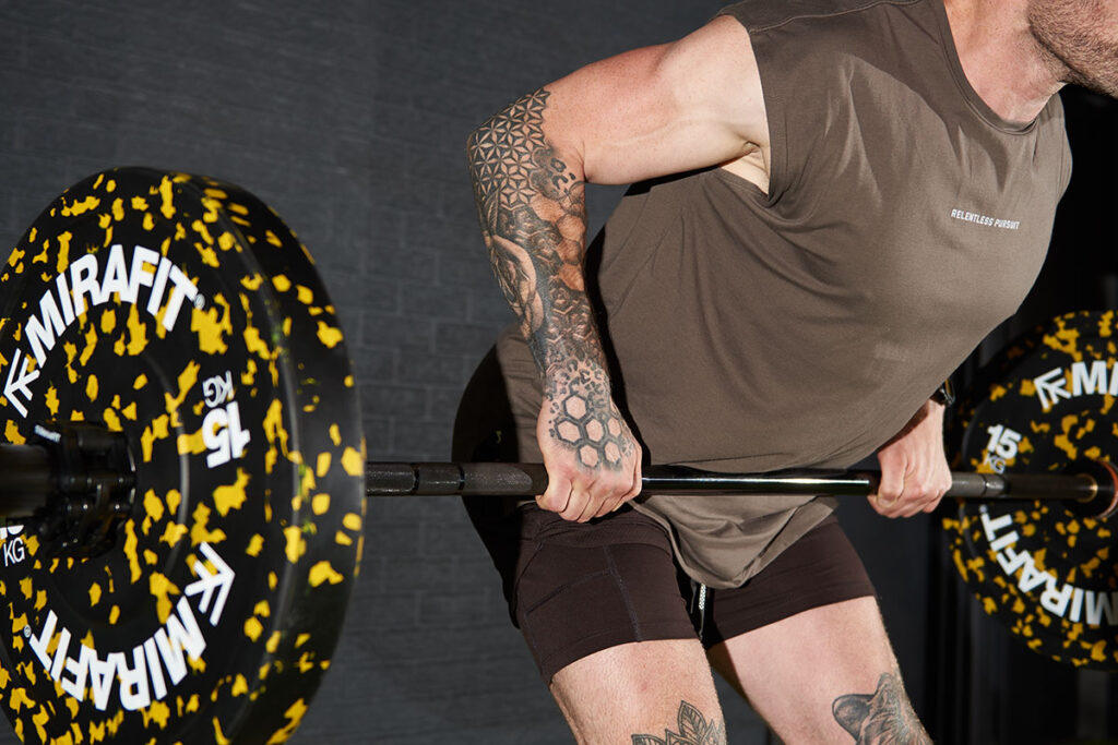 Close up of fitness expert Jay Wall with a Mirafit Olympic barbell and 15kg weight plates