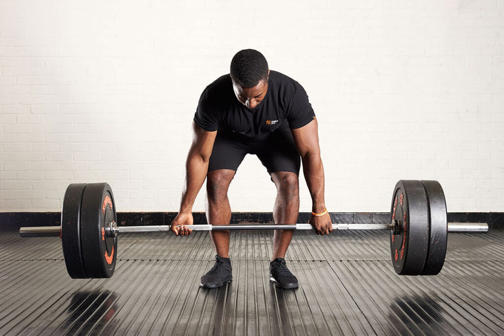 Man performing a Romanian deadlift with a Mirafit M3 barbell and bumper plates