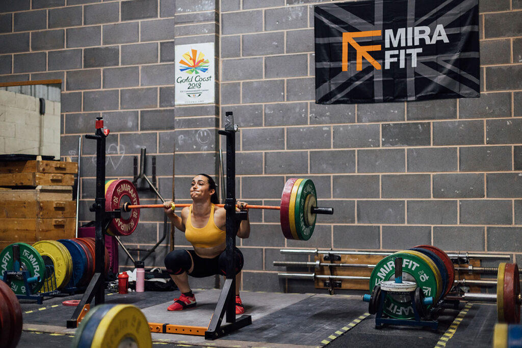 Mirafit Gym Wall Flag - Union Jack Team GB Olympic Weightlifter Sarah Davies performing a Barbell Back Squat with Mirafit Weight Plates in a gym