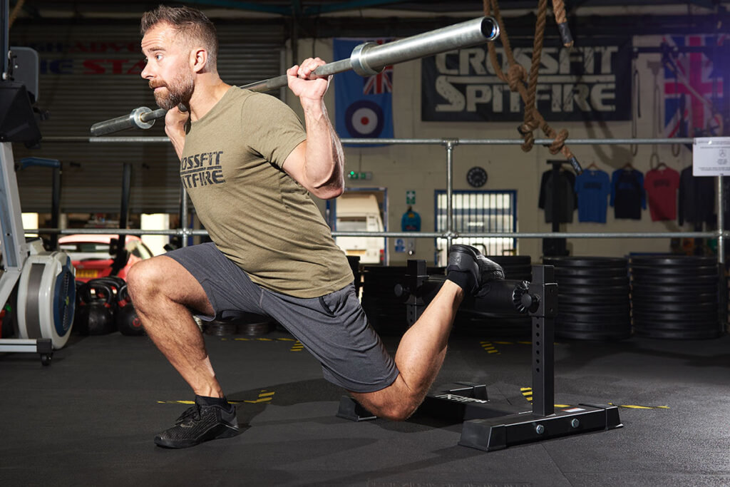 A man performing a barbell split squat with a Mirafit Single Leg Split Squat Stand in the gym