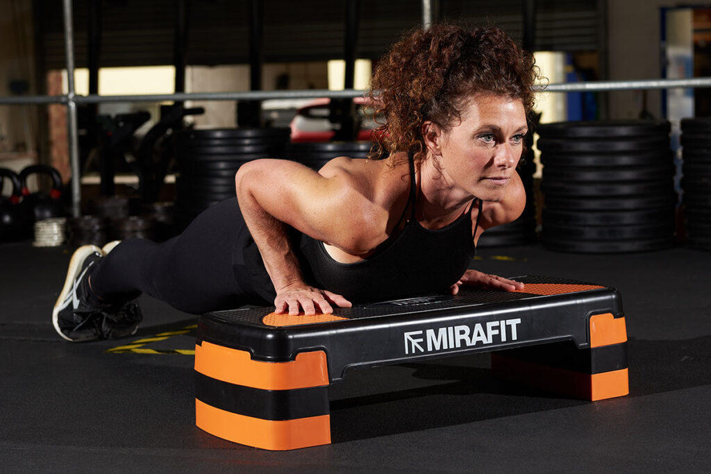 Incline push ups A woman performing an incline push up on a Mirafit Aerobic Exercise Step
