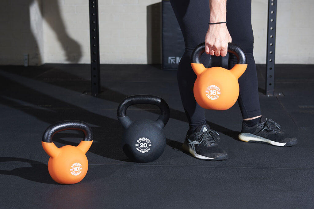 Woman holds Mirafit kettlebells in a gym