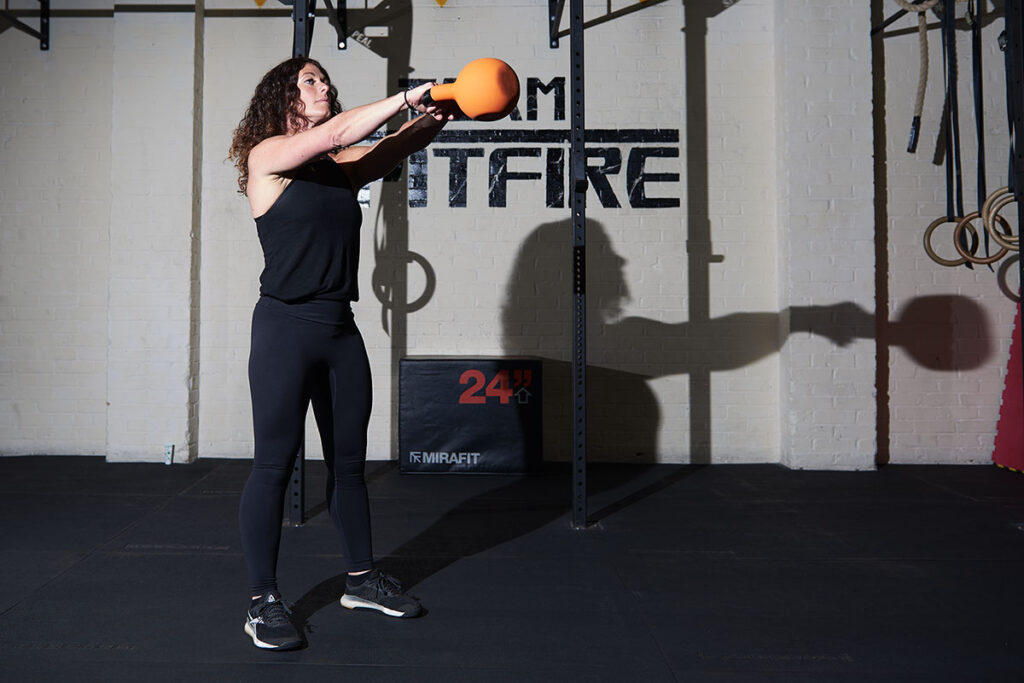 Mirafit Soft Touch Cast Iron Kettlebell Woman performing kettlebell swings with a Mirafit Soft Touch Cast Iron Kettlebell