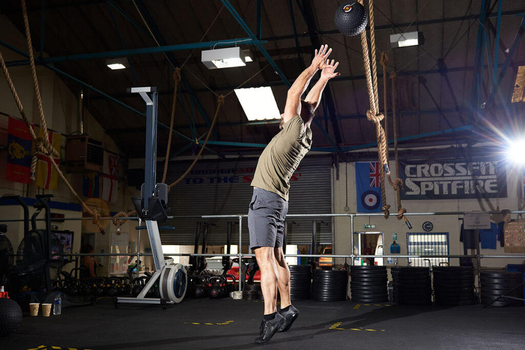 Man performing a granny toss with a Mirafit slam ball. There are many medicine ball benefits.