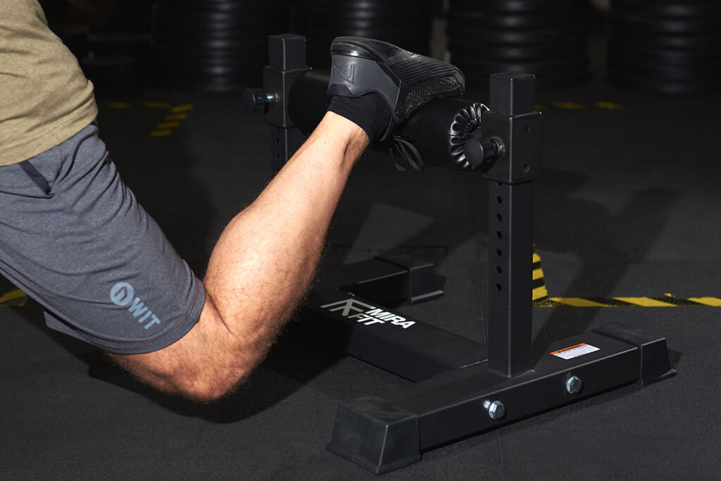 A close up of a man using a Mirafit split squat stand to do a bulgarian split squat