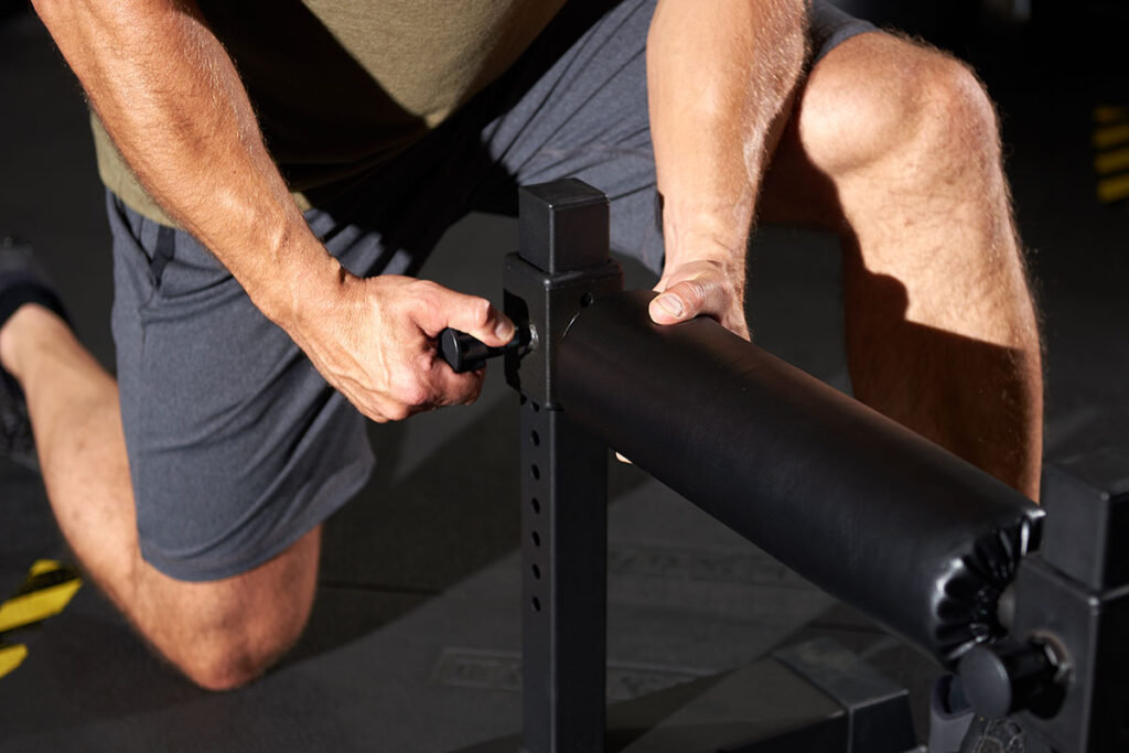 Man adjusting the Mirafit Single Leg Split Squat Stand before using it at the gym