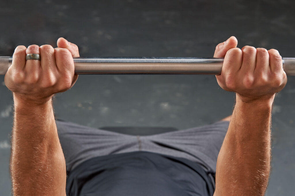 Mirafit M3 7ft 20kg Olympic Barbell Man Gripping a Mirafit Olympic Barbell for Narrow Grip Bench Press