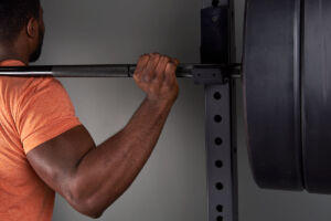 Man performing a squat with a Mirafit Olympic barbell to show hypertrophy