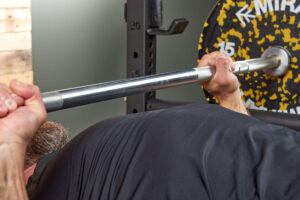 Man doing a Pause Barbell Bench Press with 15kg weight plates