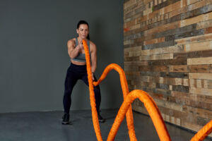 Woman using an orange Mirafit Sleeve Battle Rope