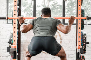 Team GB Olympic Sprinter Harry AA squatting with a Mirafit Olympic barbell