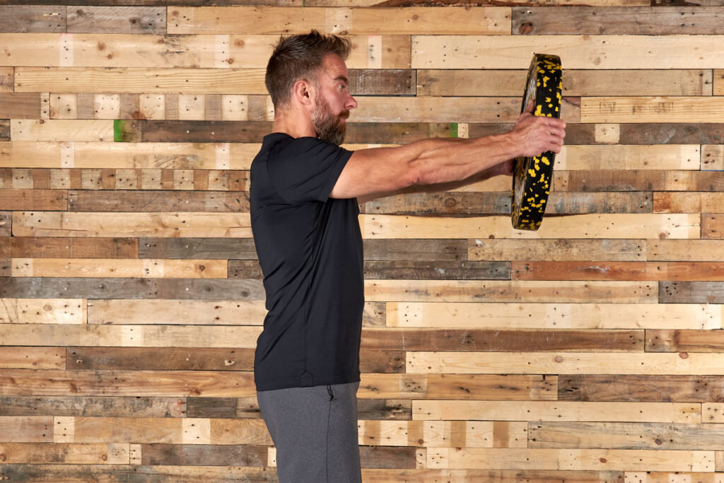 Man performing a front raise with a Mirafit 15kg Weight Plate