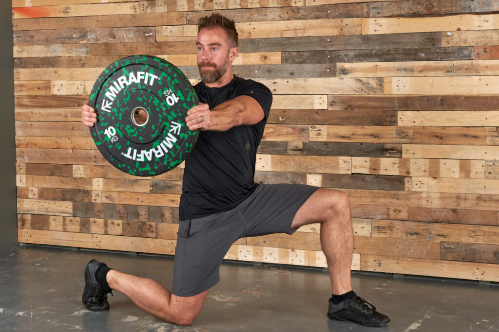 Man performing a lunge and twist with a Mirafit 10kg weight plate