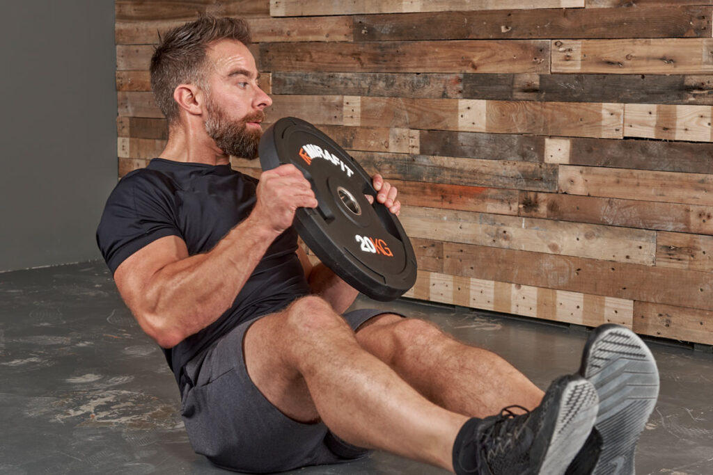 Man Performing a Russian Twist using a Mirafit 20kg Plate