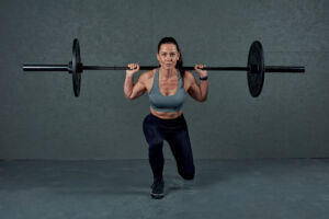 Woman performing a Barbell Split Squat with Mirafit Monochromatic Black Bumper Plates