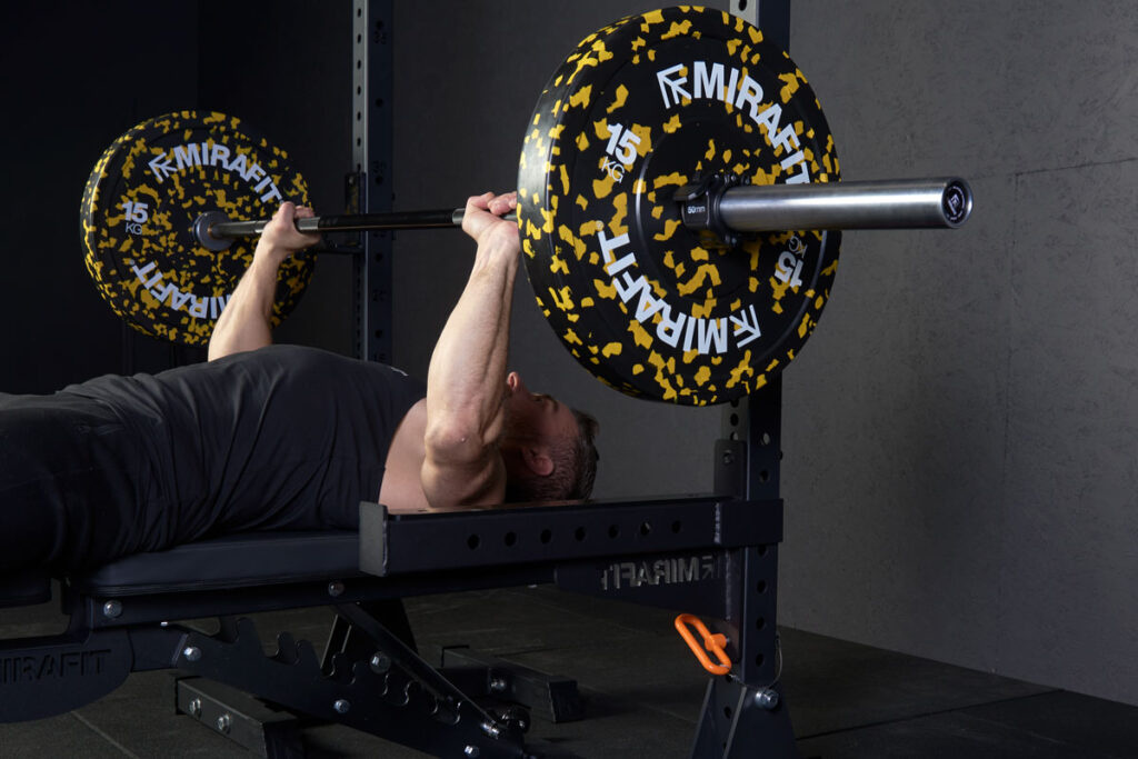 Gym Professional Performing Barbell Bench Press With Mirafit Colour Splash Bumper Plates