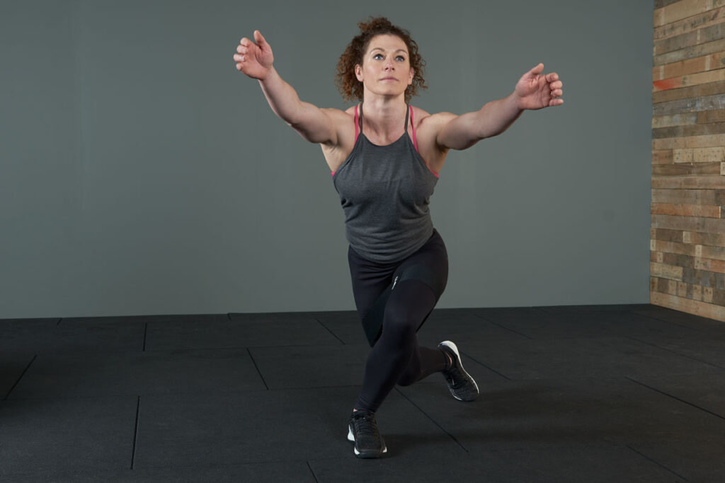 Woman performing a resistance band curtsy squat with a Mirafit fabric resistance band.