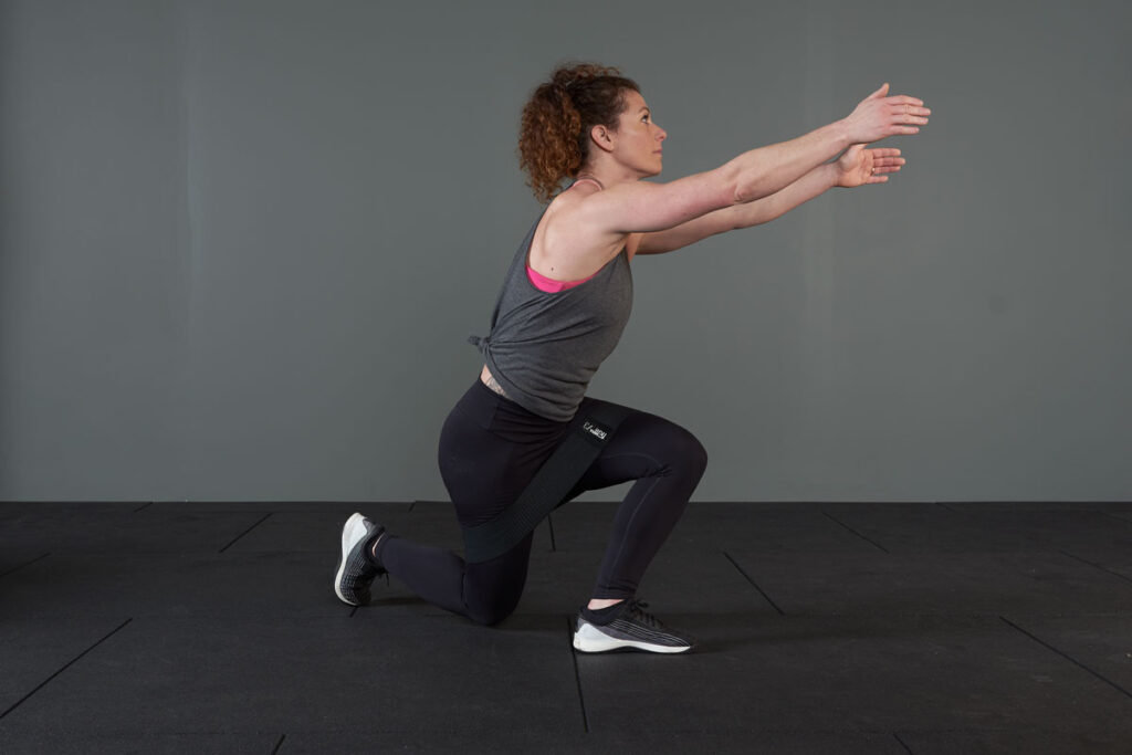 Side view of a woman performing a curtsy squat with Mirafit resistance bands.
