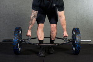 Man performing a staggered deadlift with a Mirafit trap bar and 20kg weight plates